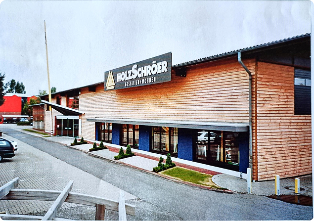 Außenansicht des modernen Holz-Schröer Fachmarkts in Dingden mit großer Holzfassade, Eingangsbereich und Ausstellungsflächen; zeigt die Weiterentwicklung vom traditionellen Sägewerk zum modernen Holzfachhandel.