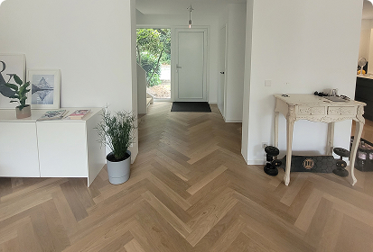 Moderner Eingangs- und Wohnbereich mit hochwertigem Fischgrät-Parkettboden; helles, minimalistisches Interior zeigt die Eleganz und Qualität der Holz-Schröer Bodenbeläge.