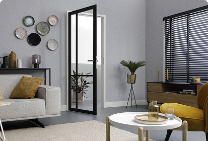 Zeitgemäß eingerichtetes Wohnzimmer mit moderner schwarzer Innenglastür, hellen Möbeln und dekorativen Elementen; zeigt die hochwertige Wohnraumgestaltung und Türlösungen von Holz-Schröer.